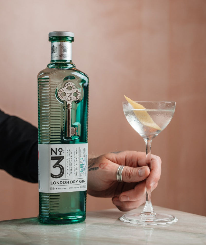 A person putting down a cocktail next to a bottle of No 3 Gin