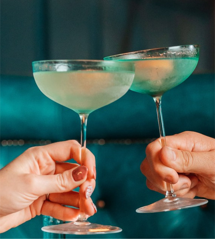 Two people clinking cocktail glasses