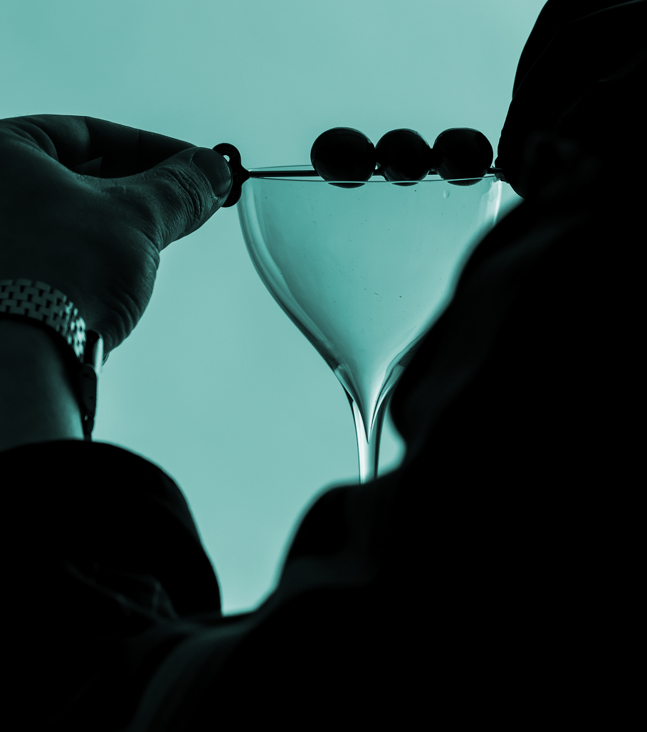 Olives being placed on a cocktail glass